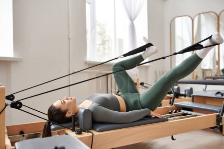 Photo for Athletic woman gracefully performs exercises during a pilates lesson. - Royalty Free Image