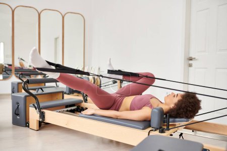 Sporty woman gracefully performs exercises during a pilates lesson.