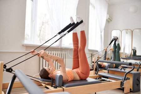 Beautiful woman gracefully performs exercises during a pilates lesson.