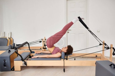 Photo for Alluring woman gracefully performs exercises during a pilates lesson. - Royalty Free Image