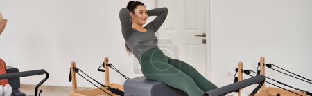 Attraktive sportliche Frau, die konzentriert und zielstrebig Pilates praktiziert.