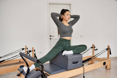 Photo for Woman in gray top and green pants works out in gym. - Royalty Free Image