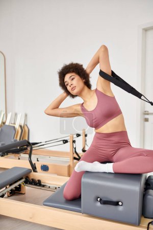 A sporty woman in pink top and leggings on pilates lesson.
