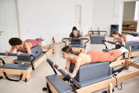 Photo for Sporty women engaging in a Pilates session in a bright room. - Royalty Free Image
