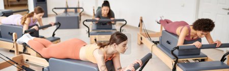 Eine Gruppe ziemlich sportlicher Frauen macht während einer Pilates-Stunde im Fitnessstudio Übungen.
