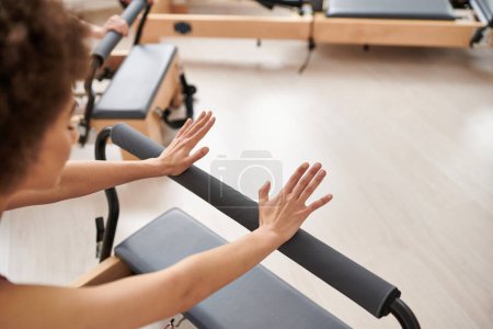 A sporty woman stretches her arms in a gym during a pilates lesson.