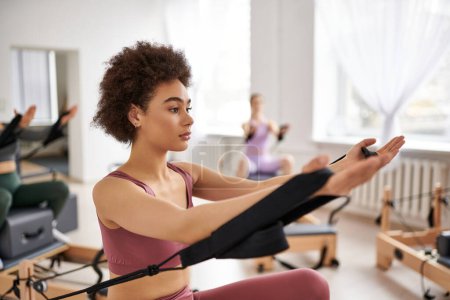 A group of pretty sporty women in a gym doing exercises during a pilates lesson.