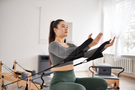 Appealing woman in cozy attire actively exercising on pilates lesson.