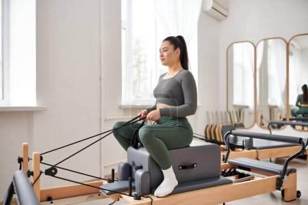 Attractive woman in cozy attire actively exercising on pilates lesson.
