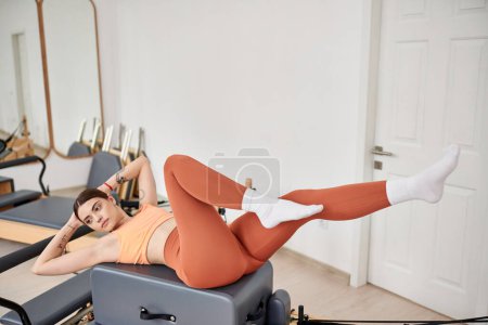 Téléchargez les photos : Femme séduisante en tenue de sport confortable pratiquant pendant la leçon de pilates. - en image libre de droit