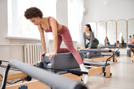Sportliche Frauen in kuscheliger Kleidung üben gemeinsam Pilates im Fitnessstudio.