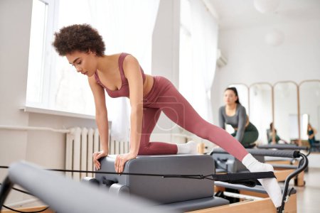 Photo for Young women in cozy attire practicing pilates in a gym together. - Royalty Free Image