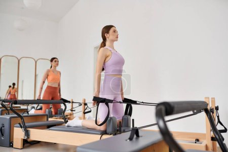 Sportliche Frauen üben anmutig Pilates in einem Fitnessstudio zusammen.