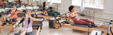 Athletic women gracefully performing exercises during a Pilates session in a gym.