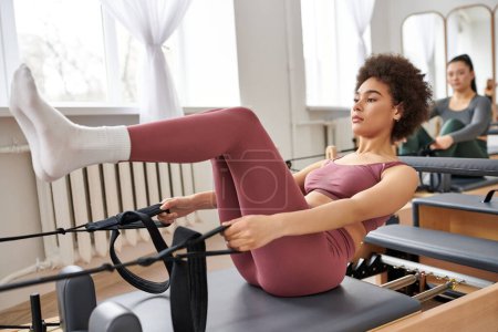 Alluring women gracefully practicing pilates in a gym together.
