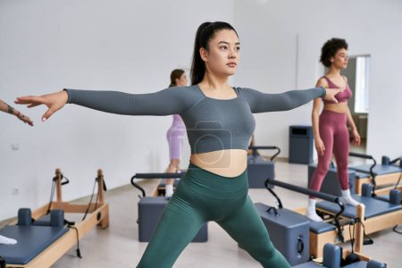 A group of pretty sporty women engaging in a lively pilates class.