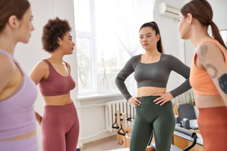 Sportliche Frauen machen Pause bei Pilates-Stunde im Fitnessstudio.