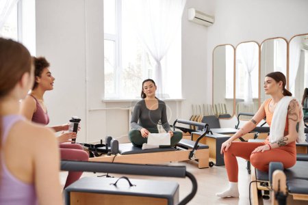 Beautiful women taking break during pilates lesson in gym.