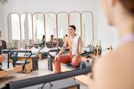Appealing women spending time together on pilates lesson in gym, relaxing.