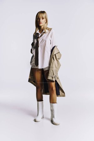Stylish woman combines short shorts and trench coat in striking pose.