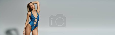 Téléchargez les photos : A stylish, fashionable woman with blonde hair striking a pose in a sophisticated blue swimsuit. - en image libre de droit