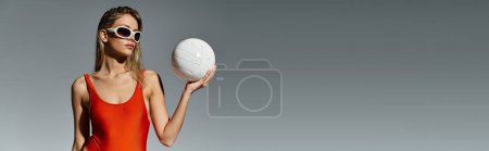 Téléchargez les photos : Femme blonde en maillot de bain orange tendance jouant avec une balle blanche. - en image libre de droit