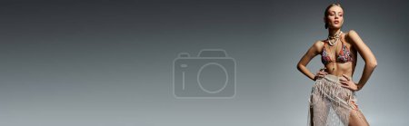 Photo for Stylish blonde woman in bikini striking a pose on gray background. - Royalty Free Image