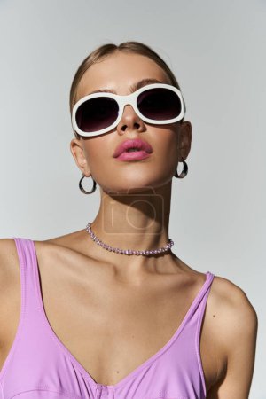 Foto de Mujer rubia en top morado y gafas de sol exudando confianza. - Imagen libre de derechos