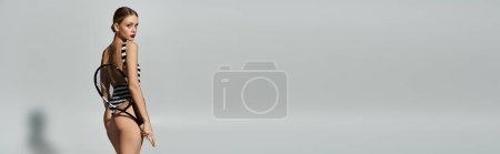 Foto de Mujer de moda con pelo rubio en traje de baño a rayas sobre fondo gris. - Imagen libre de derechos