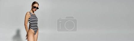 Téléchargez les photos : Femme blonde élégante posant dans un maillot de bain rayé noir et blanc à la mode. - en image libre de droit