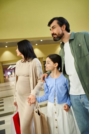 Eine glückliche Familie mit Einkaufstüten, die einen Tag im Einkaufszentrum genießt, während sie zusammen spazieren gehen.