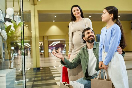 Eine fröhliche Familie spaziert mit bunten Einkaufstüten durch ein Einkaufszentrum.