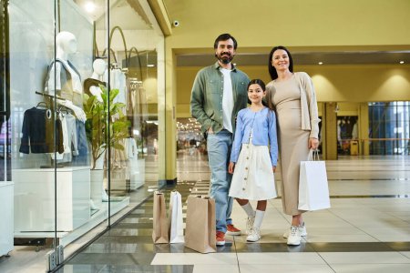 Une famille joyeuse, chargée de sacs à provisions, profitant d'une journée de thérapie au détail dans un centre commercial animé.
