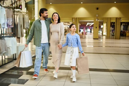 A happy family with shopping bags walks through a bustling mall on a fun weekend outing together.