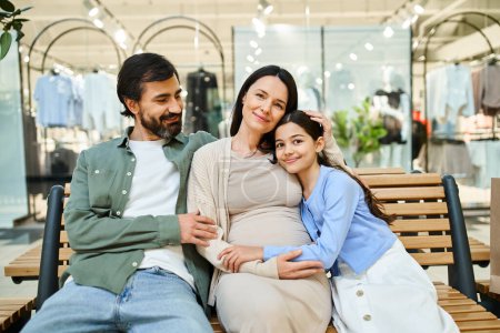 A pregnant woman and her daughter sit on a bench in a shopping mall, enjoying a bonding moment during their shopping weekend.