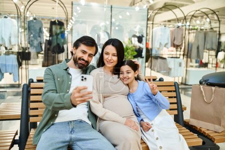 Foto de Una familia alegre captura un momento en un banco en un centro comercial, sonriendo mientras se toman una selfie juntos. - Imagen libre de derechos
