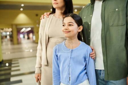 Téléchargez les photos : Une famille avec leur fille explore joyeusement un centre commercial ensemble pendant un week-end shopping. - en image libre de droit