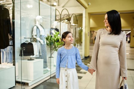 A pregnant woman and her daughter exploring a shopping mall together, enjoying a family bonding experience.