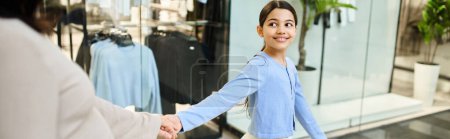 mother and daughter enthusiastically walk in a store while shopping.