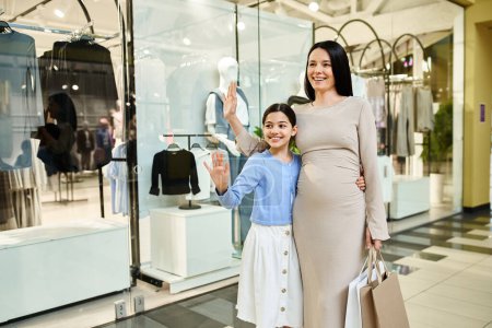 A pregnant woman and her daughter share a joyful moment while strolling through a bustling shopping mall.