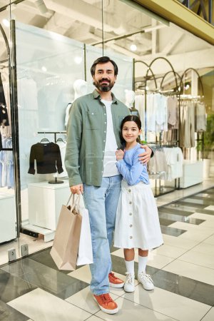 A man and his daughter stand together in a bustling shopping mall, enjoying a bonding moment on a weekend outing.