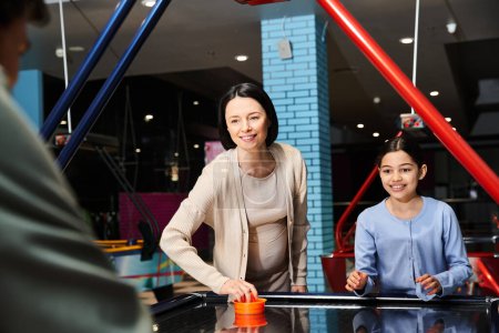 A lively family enjoys a competitive game of air hockey in a bustling mall gaming zone on the weekend.