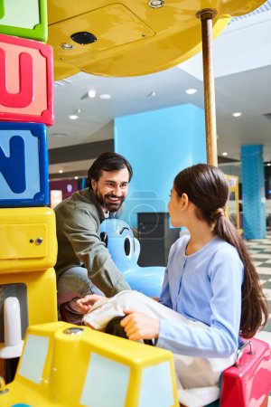 Téléchargez les photos : Father and child happily play with a toy car in a malls gaming zone during the weekend. - en image libre de droit