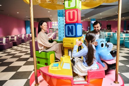 Eine fröhliche Familie dreht sich in einem lebhaften Spielwarengeschäft auf einem Karussell und lacht während eines Wochenendausflugs in der Spielzone des Einkaufszentrums.