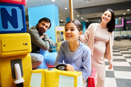 Eine schwangere Frau und ihre Tochter lachen und spielen während eines lustigen Wochenendausflugs in einem Einkaufszentrum.