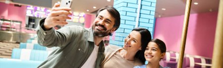 Téléchargez les photos : Une famille heureuse de quatre personnes aime prendre un selfie dans la zone de jeu des centres commerciaux pendant un week-end amusant. - en image libre de droit