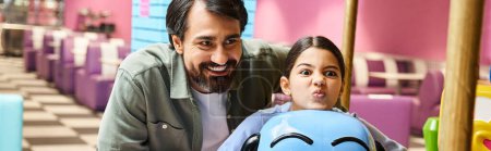 Téléchargez les photos : Un père et un enfant heureux assis sur un jouet dans une aire de jeux pour enfants dans un centre commercial pendant le week-end. - en image libre de droit