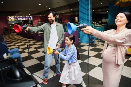 Une famille heureuse, parents et enfants, plongés dans une compétition de jeu animée dans la zone de jeu des centres commerciaux un week-end.