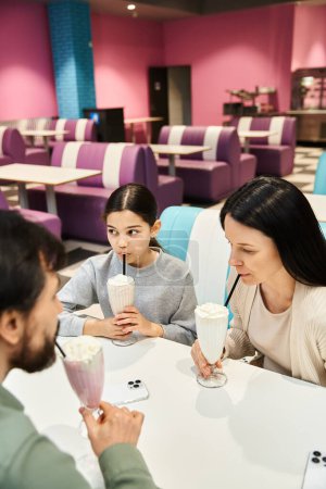A family enthusiastically enjoying delicious milkshakes at a modern restaurant during the weekend.