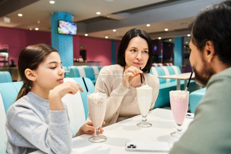 Téléchargez les photos : Une famille heureuse profite d'un moment de qualité dans un restaurant, assis ensemble à une table - en image libre de droit